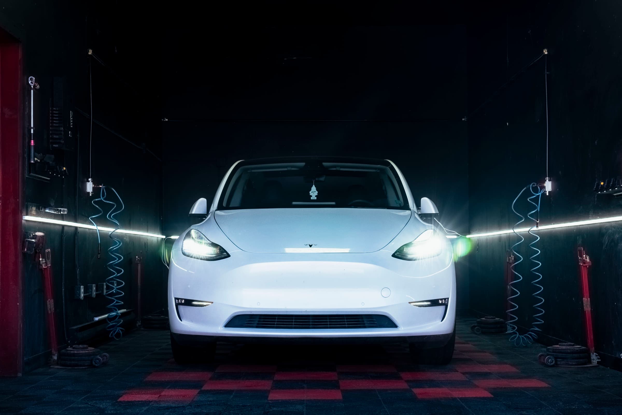 Tesla Model Y front-on in the PitStop & Go service bay under moody dark lighting