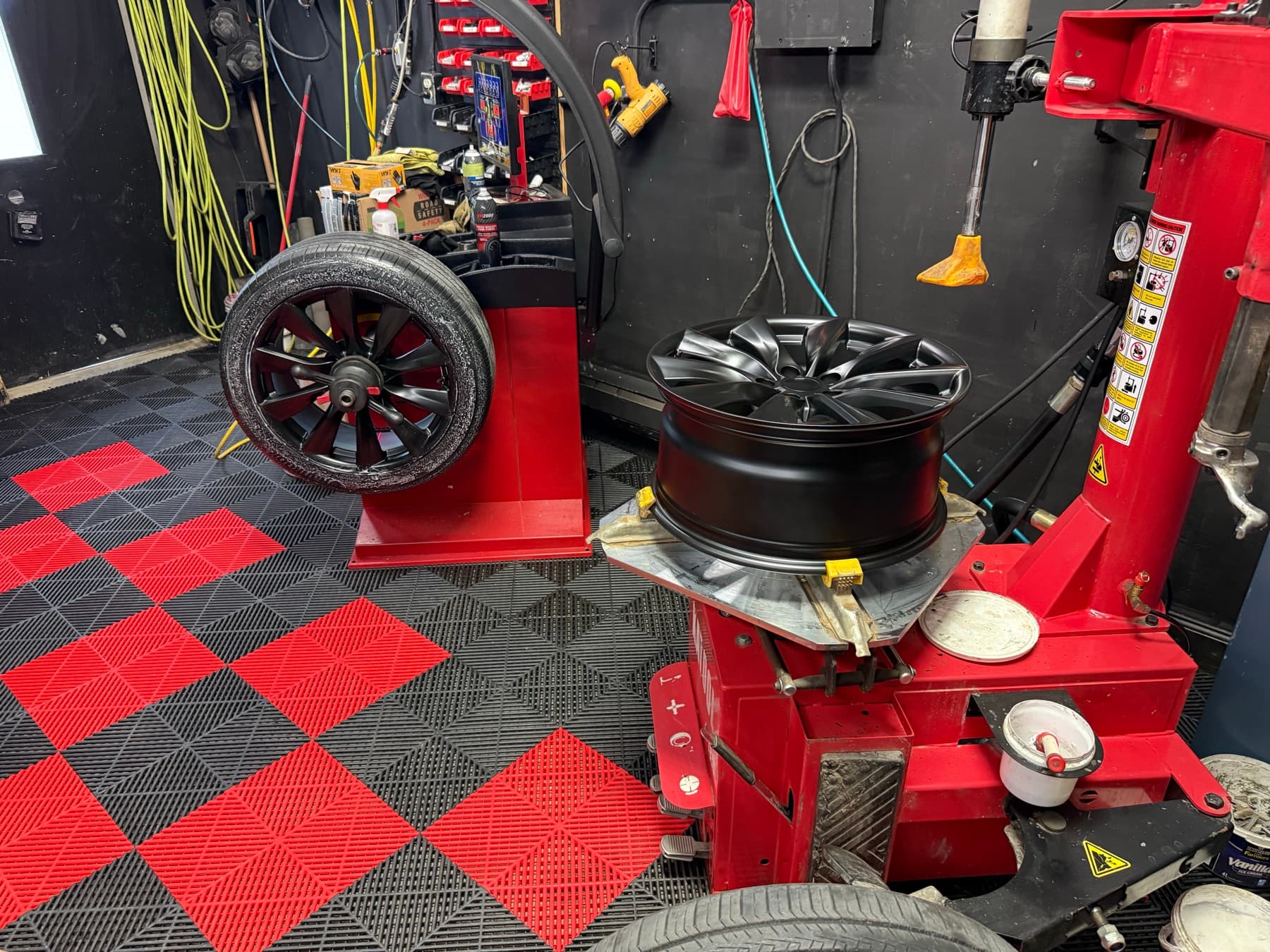 Wide shop floor at PitStop & Go, wheel balancer on the left, tire mounting machine on the right